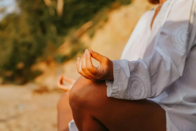 A close-up of a person meditating outdoors, capturing mindfulness at sunset on a beach.