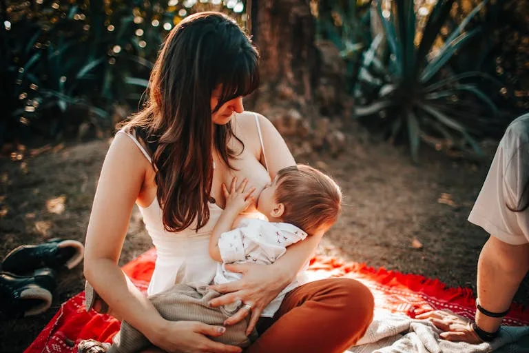 Vrouw geeft buiten op een zonnige dag borstvoeding aan haar zorgen en liefde