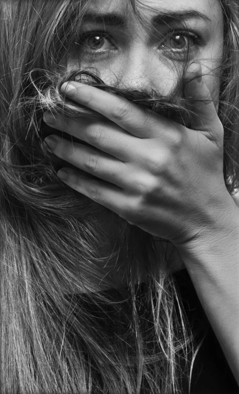 Zwart wit foto van angstige starre blik van vrouw met hand voor mond. Depressie, angst, op de rand.. Foto: krivitskiy