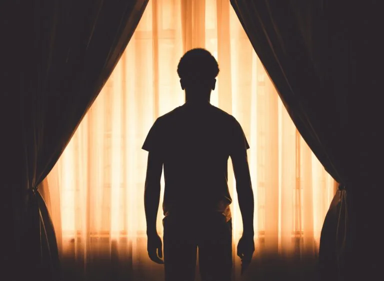 Silhouet van een man die voor het raam staat en naar buiten kijkt. foto: Vitor