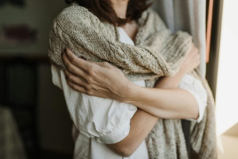 Handen houden zachtjes gevouwen natuurlijk linnen vast in warm daglicht, focus op textuur en tactiel contact met de stof Foto: Arina Krasnikova