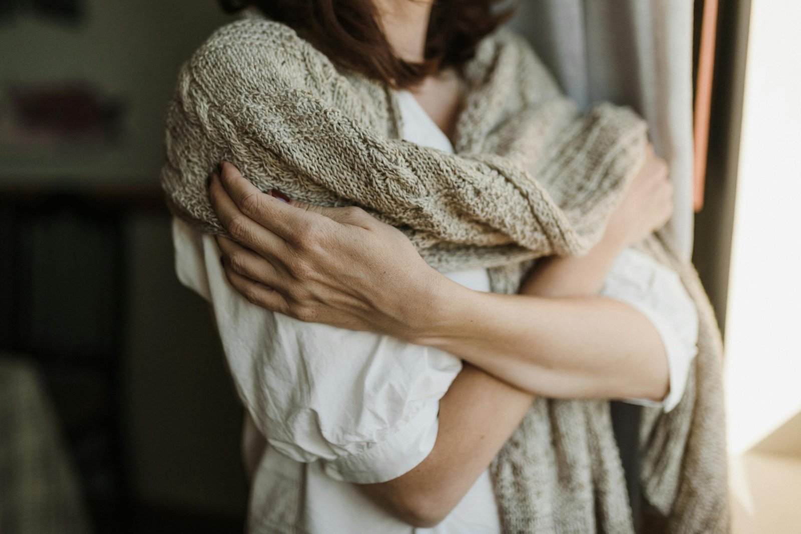 Handen houden zachtjes gevouwen natuurlijk linnen vast in warm daglicht, focus op textuur en tactiel contact met de stof Foto: Arina Krasnikova
