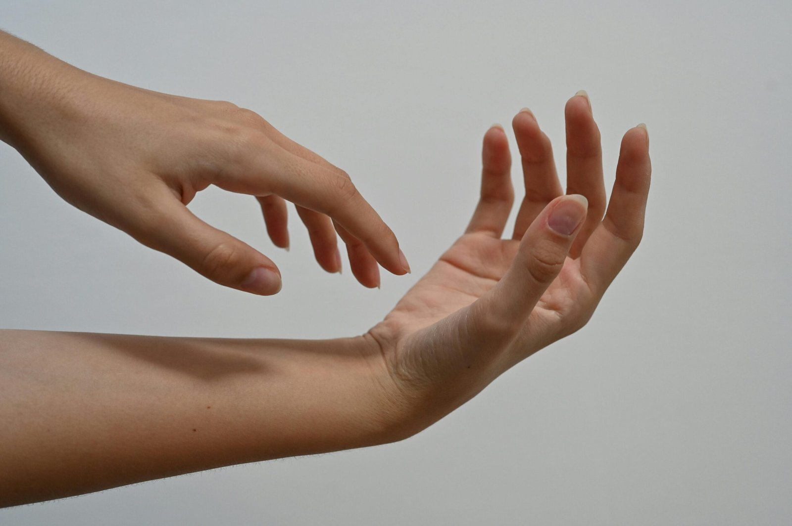 Twee handen met natuurlijke, ongelakte nagels in zachte omhelzing tegen neutrale achtergrond, symbool voor bewuste nagelverzorging foto: aloevera