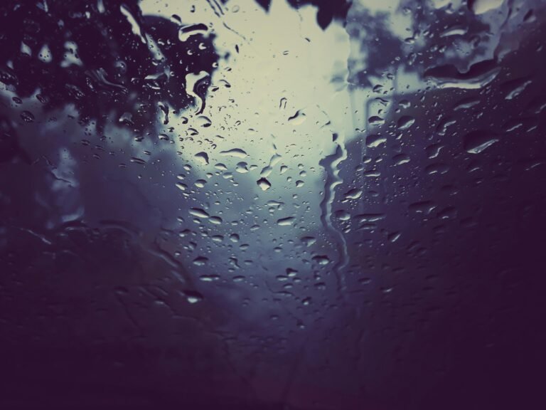 Regendruppels op een raam met een wazige buitenwereld daarachter, een stille grens tussen binnen en buiten die verwerking en integratie suggereert. foto: Ruatsanga hmar