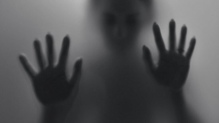 Silhouet van een persoon achter matglas met handen tegen het oppervlak, symbool voor innerlijke spanning en een lichaam dat alarm slaat zonder zichtbare oorzaak. foto: Wunderbilder