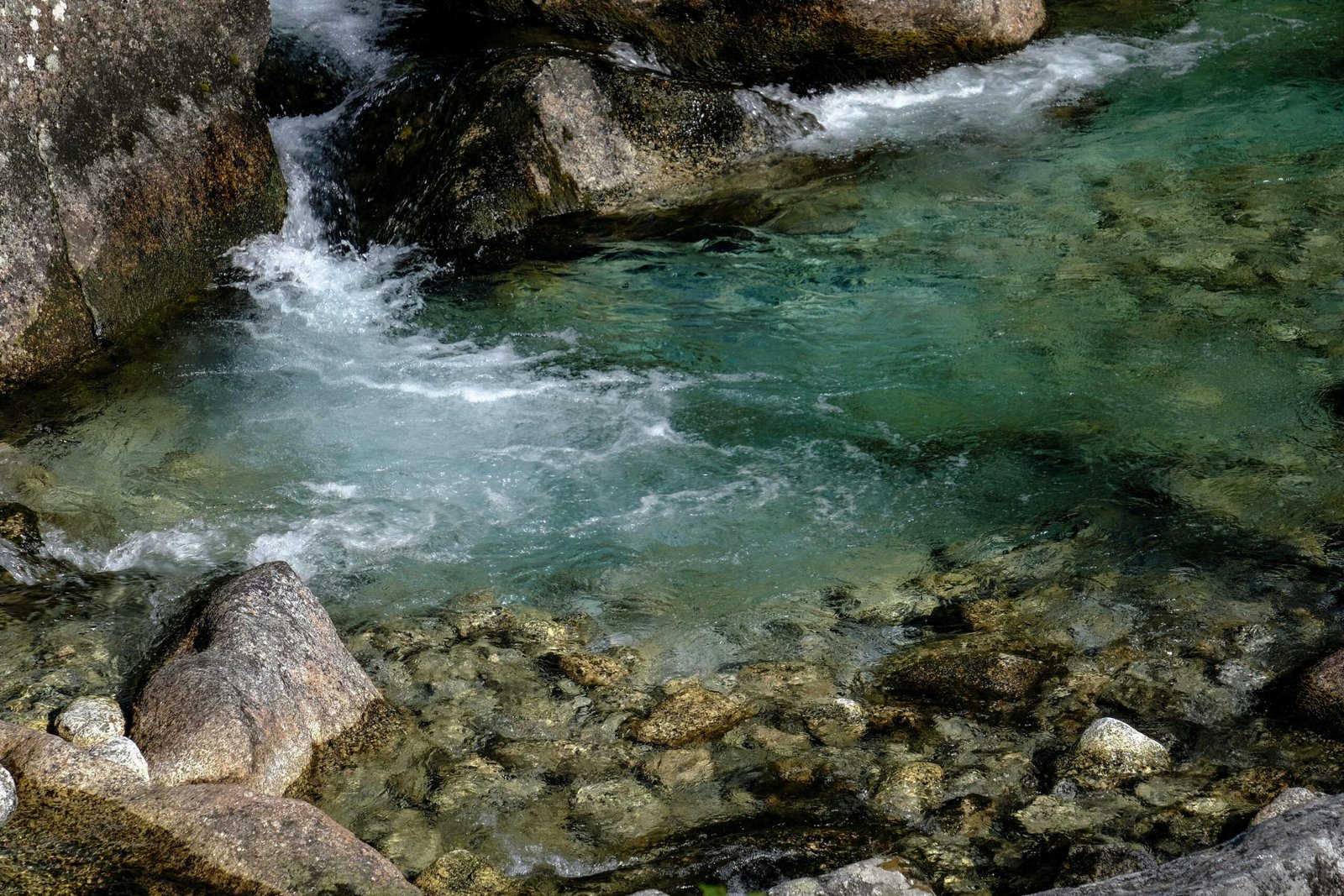 Helder stromend water tussen stenen in een bergbeek als symbool voor natuurlijke stroming in het lichaam en het lymfestelsel. foto: Franceco Ungaro