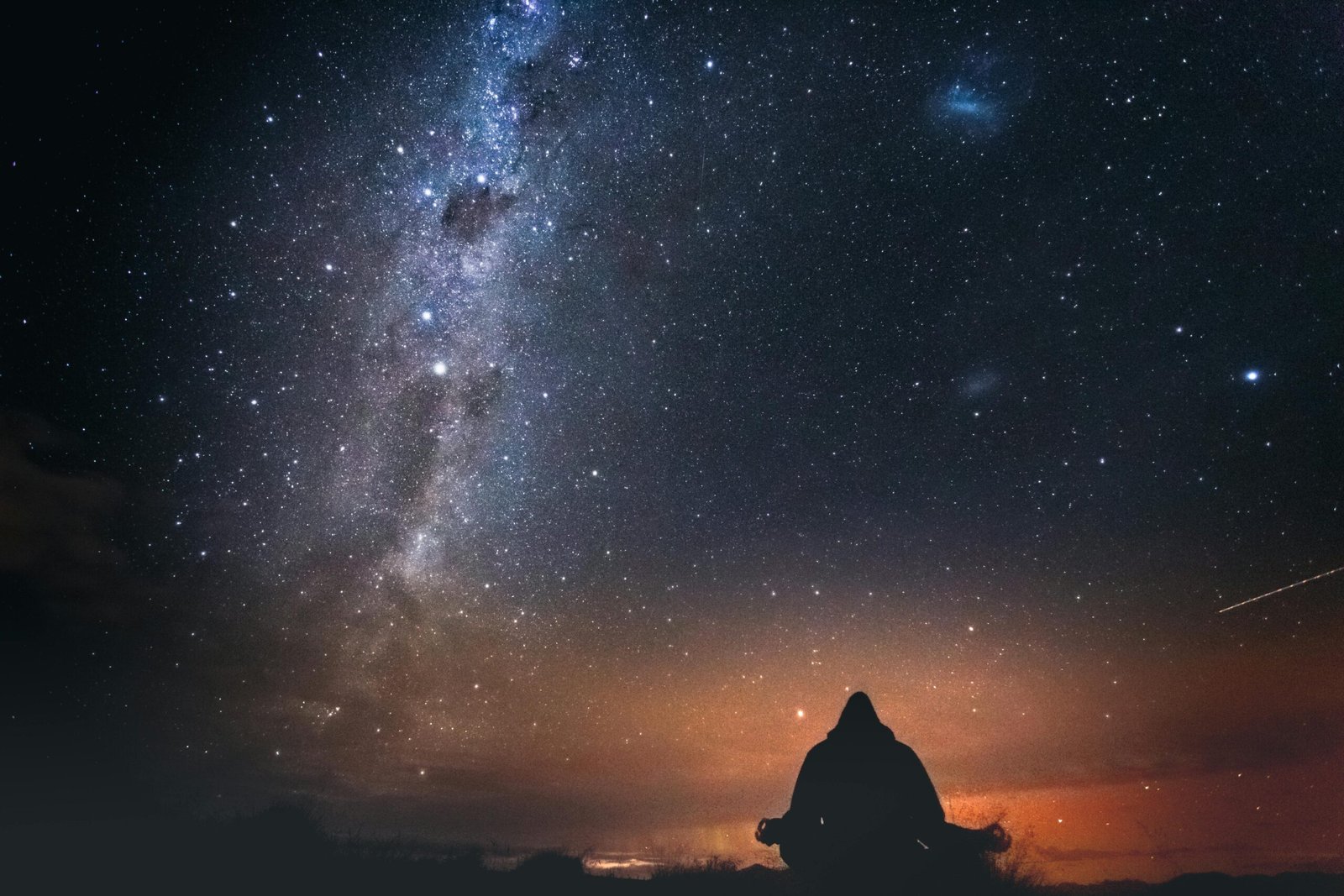 Persoon die in stilte naar de sterrenhemel kijkt onder de melkweg, symbool voor reflectie en een astrologisch gesprek dat nieuwe inzichten opent. foto: Marek Piwnicki